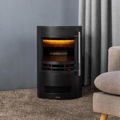 a black stove sitting on top of a carpeted floor next to a gray chair