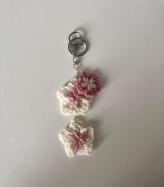 two crocheted flowers are attached to a keychain on a white surface