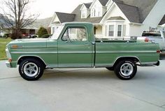 a green pick up truck parked in front of a house