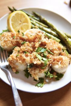 a white plate topped with scallops and asparagus next to a fork