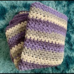 two purple and white crocheted blankets sitting on top of a blue blanketed floor