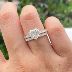 a woman's hand with a diamond ring on top of her wedding band and an engagement ring in the middle