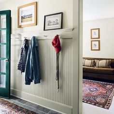 a coat rack with coats hanging on it next to a couch and rug in a living room