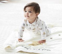 a baby laying on top of a white blanket