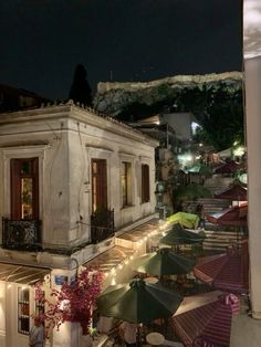 an old building with tables and umbrellas in front of it on a street at night