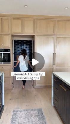 a woman standing in an open kitchen with lots of cupboards and drawers on the wall