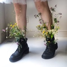 two pairs of shoes with flowers in them are standing on a white floor next to each other