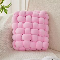 a pink pillow sitting on top of a white couch