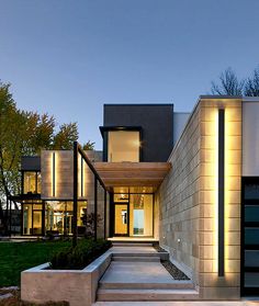 a modern house with steps leading to the front door and entry way at night time