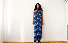 a woman standing in front of a white wall wearing a blue and white striped dress