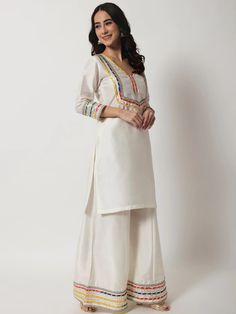 This is a beautiful 3 piece suit set. It comes with straight cut kurta has 3/4th sleeves, round neck, calf length teamed with croma silk palazzo pants and a multi color lehriya print organza dupatta with golden lace detailing. 3 piece set Color- Ivory Work- Gota & Embellished Detailing Kurti Length-34 inch Kurta Fabric-Croma Silk Bottom Fabric-Croma Silk Dupatta Fabric-Organza Sleeves-3/4th Sleeves Neck-Round Neck Care - Dry Clean Kurta Palazzo Set, Golden Lace, Short Kurti, Organza Sleeves, Palazzo Set, Silk Bottoms, Kurta Designs Women, Dupatta Set, Dream Wedding Ideas Dresses