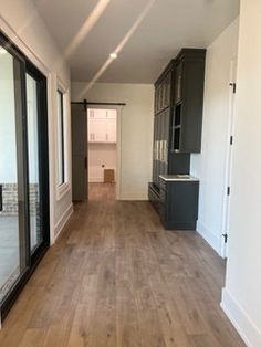 an empty room with wood flooring and sliding glass doors leading into the kitchen area