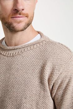 a man wearing a hat and sweater looking at the camera