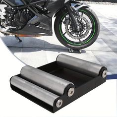 a motorcycle is parked on the sidewalk with two rolls of black paper in front of it