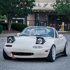 a white sports car parked in front of a building