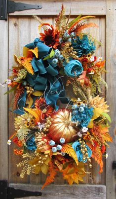 an autumn wreath with blue and orange flowers on a wooden door, ready to be hung by the front door