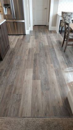 a kitchen with wood flooring and stainless steel appliances in the back ground is a dining room table