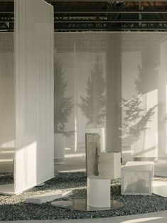 an empty room with white columns and trees in the backgrounge, surrounded by gravel