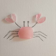 a piece of artwork made out of sea glass with two hands holding an object in the shape of a crab