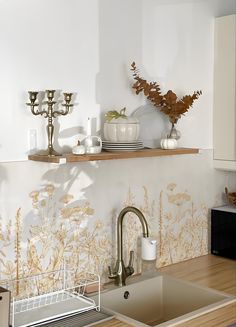 a kitchen sink sitting under a window next to a shelf with candles and dishes on it