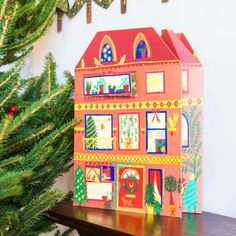 a doll house sitting on top of a wooden table next to a christmas tree and decorations