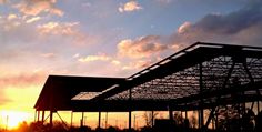 the sun is setting behind a building with metal roofing and beams on it's sides