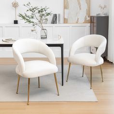 two white chairs sitting next to each other on top of a wooden floor in front of a table