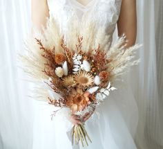 a bride holding a bouquet of dried flowers