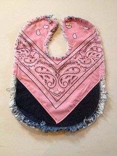 a pink bandana with black and blue trim hanging on a wall next to a pair of scissors