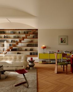 a living room filled with furniture and lots of bookshelves on the wall behind it