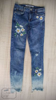 a pair of jeans with daisies painted on them