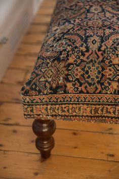 an old rug is sitting on top of a wooden bench in the middle of a room