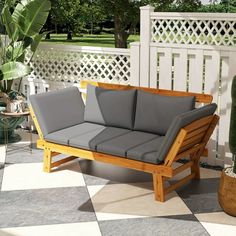 a wooden couch sitting on top of a tiled floor next to a potted plant