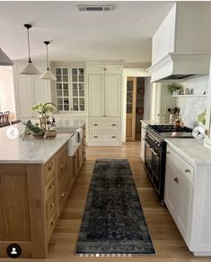 a large kitchen with white cabinets and wood flooring is seen in this image from the front door