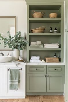 a bathroom with green cabinets and white towels on the shelf, along with a plant