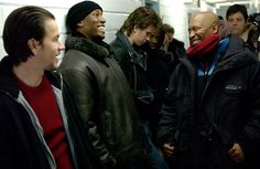 a group of men standing next to each other on a subway platform, all smiling