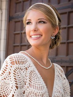 a woman in a white dress with pearls on her head