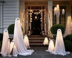 a group of ghost statues in front of a house decorated for halloween with lights and decorations