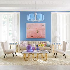 a living room with blue walls, white furniture and pink painting on the wall in it