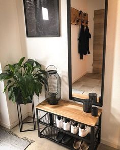 a mirror sitting on top of a wooden shelf next to a potted plant and shoe rack