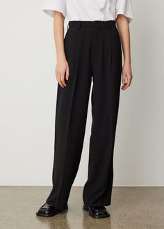 Incu Collection finesses a favourite pant into perfection. The Beau Pleat Trousers are crafted from black crepe suiting that provides maximum versatility. They’re cut to a high-rise waist, enhanced with a single pleat for a comfortable play on proportion and finished with a concealed hook, zip and button closure for a sleek look. Tuck in the Classico Recycled Unisex T-Shirt to tie in the relaxed look.  - Black crepe fabrication- High waist- Belt loop waistband - Single pleat- Coin pocket - Front side welt pockets - Concealed hook, button and zip closure - Back welt pockets with button closure- Relaxed fit Materials: 100% Polyester. Care: Cold machine wash. Dry cleanable. Warm iron. Sizing: Item fits true to size. Model wears a size 8 and is 176cm/5'7". Black Suit Pants, Classic Black Pleated Pants, Black Trousers With Pockets, Classic Trousers Man, Pleated Trousers Men, Black Pleated Trousers, Luxury Pleated Black Pants, Mens Single Pleat Pants, Utility Pants Men