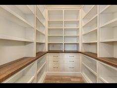 an empty walk - in closet with white shelves and wood flooring on the side