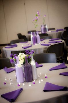 purple and white flowers are in vases on top of the tables at this wedding reception