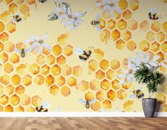 a wall with bees and honeycombs painted on it, next to a potted plant