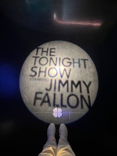 the tonight show starring jimmy falcon is projected on a round sign in front of a person's feet