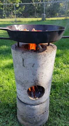 an outdoor fire pit sitting on top of a lush green field