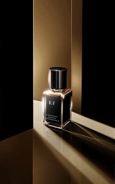 a bottle of k v perfume sitting on top of a shiny table next to a mirror