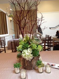 there is a vase with flowers and candles on the table in front of some branches