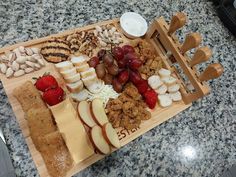 an assortment of cheeses, crackers, fruit and nuts on a cutting board