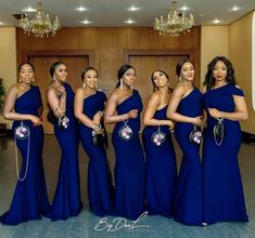 a group of women standing next to each other wearing blue dresses and holding purses